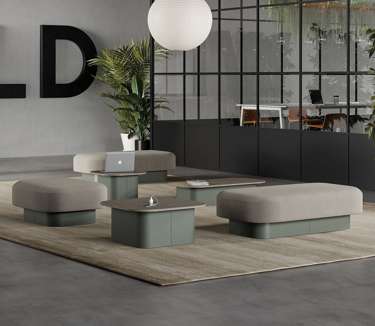 Salon de bureau moderne avec des banquettes basses rembourrées, des tables basses Afina de Ramos Bassols, un ordinateur portable et une cloche sur un tapis beige. Grande plante, mur de verre et salle de réunion en arrière-plan. Décor minimaliste.