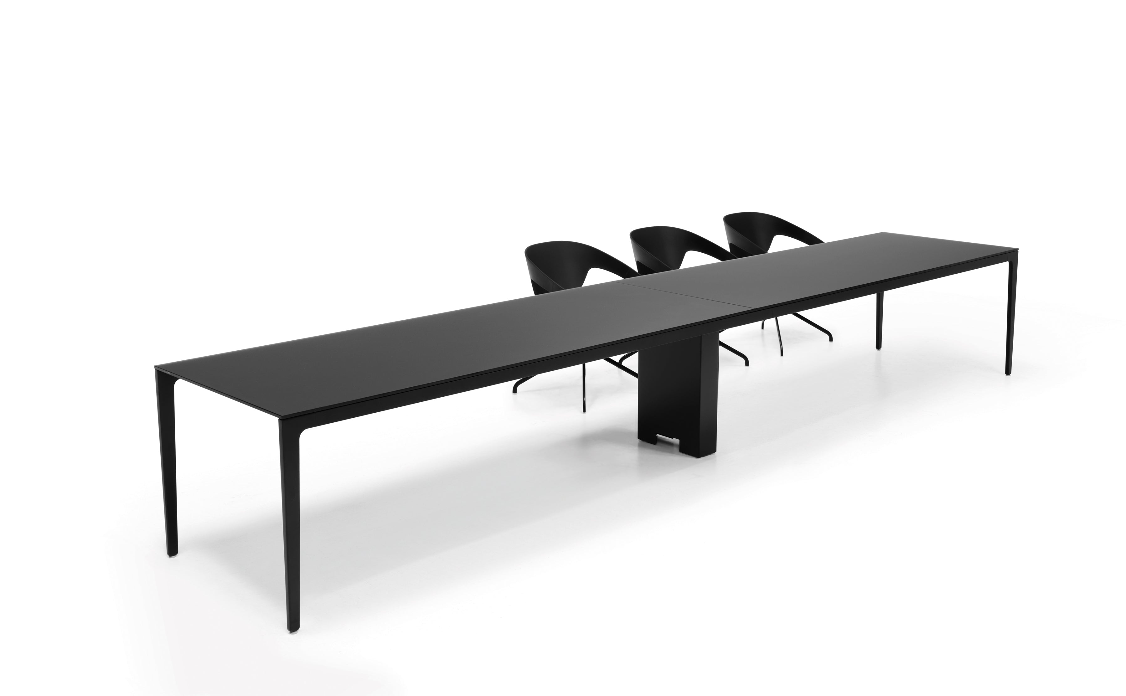 Les Tables de réunion modulables Alplus de Marco Zito se composent d'une longue table rectangulaire noire aux pieds fins et de trois chaises modernes noires d'un côté, le tout sur un fond blanc uni, mettant en valeur son système modulaire flexible.