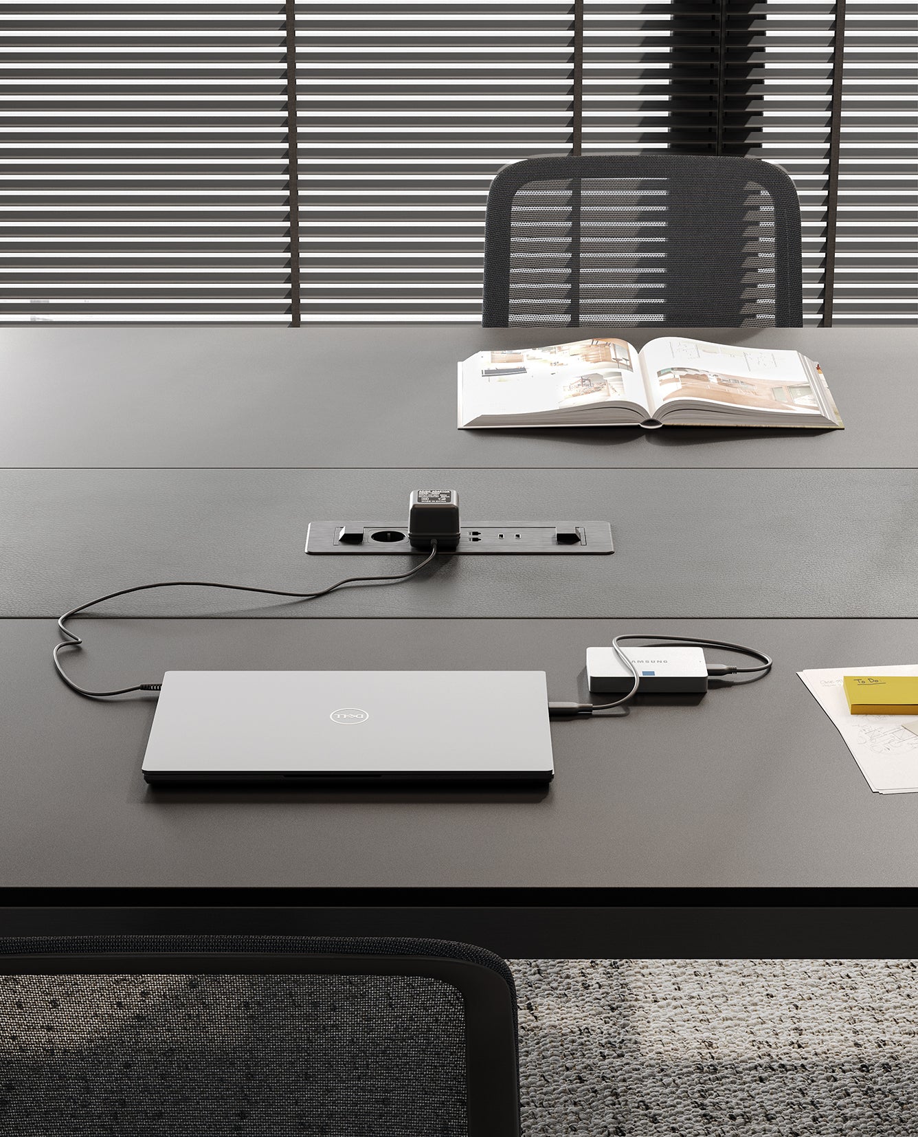 Les Tables de réunion modulables Alplus de Marco Zito présentent un espace de travail moderne avec un ordinateur portable fermé, des câbles de recharge, un magazine ouvert et un document sur le dessus. La gestion intégrée des câbles garantit un environnement sans encombrement et un style élégant.