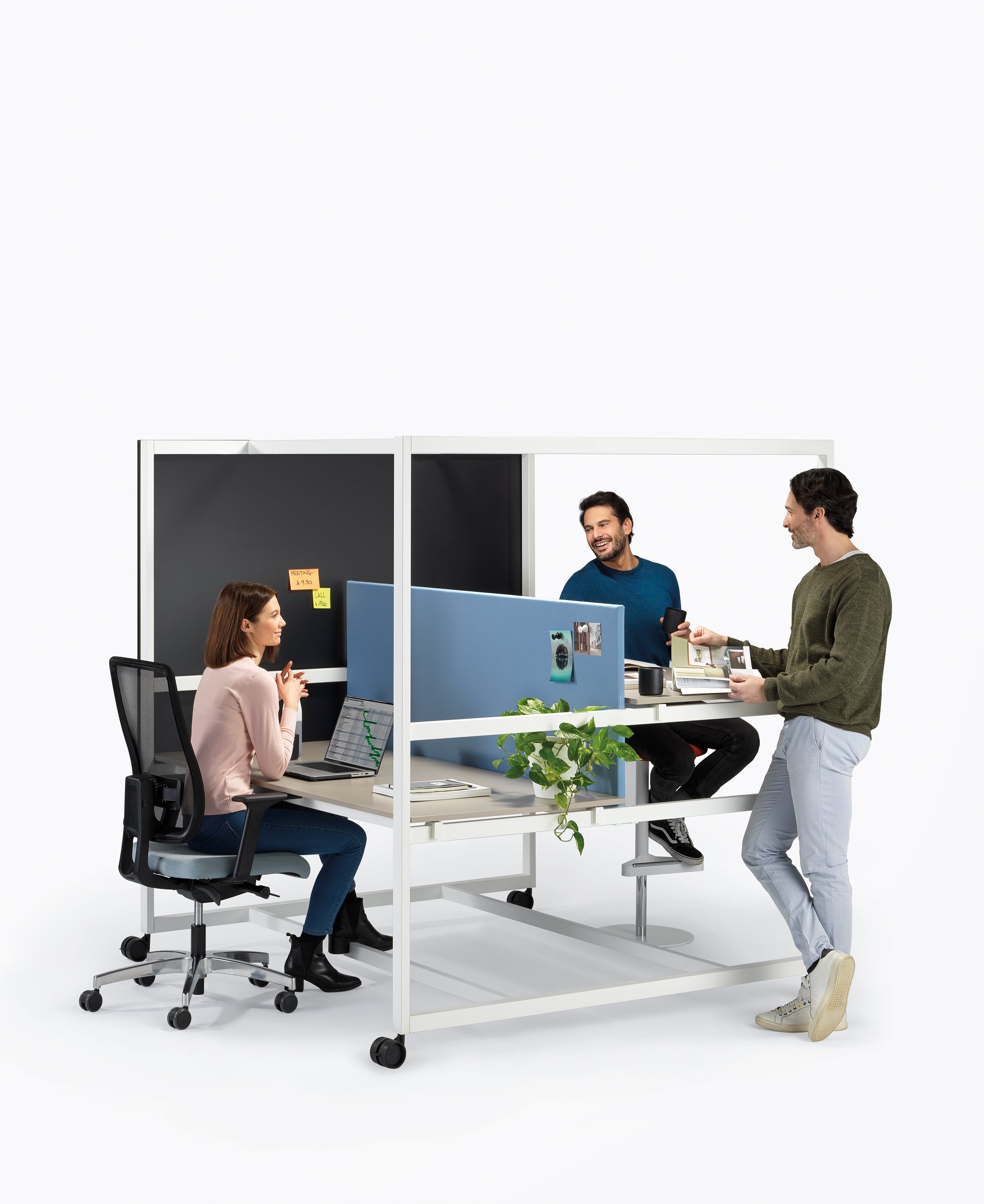 Trois collègues collaborent à la Table haute Nomad de Progetto CMR. Une femme travaille sur son ordinateur portable tandis que deux hommes conversent à proximité avec des tasses de café. Des panneaux de séparation offrent une certaine intimité et une plante ajoute une touche naturelle au poste de travail.
