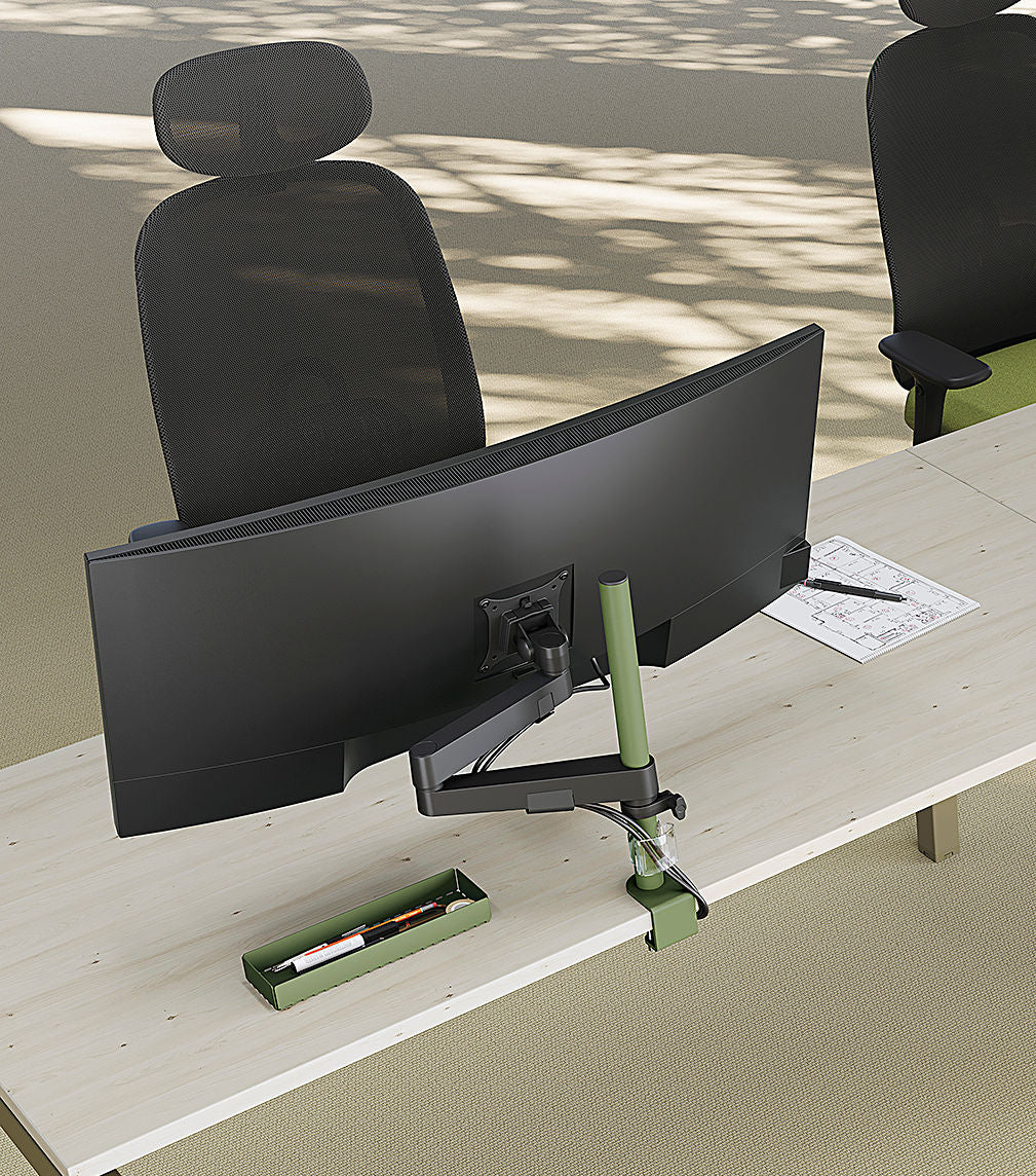 Un bureau moderne avec un grand écran incurvé sur le Bras écran CLICK d'Attitudes Bureaux, une chaise en maille noire, un plumier vert avec de la papeterie et du papier diagramme - idéal pour une installation rapide sur une surface en bois clair.