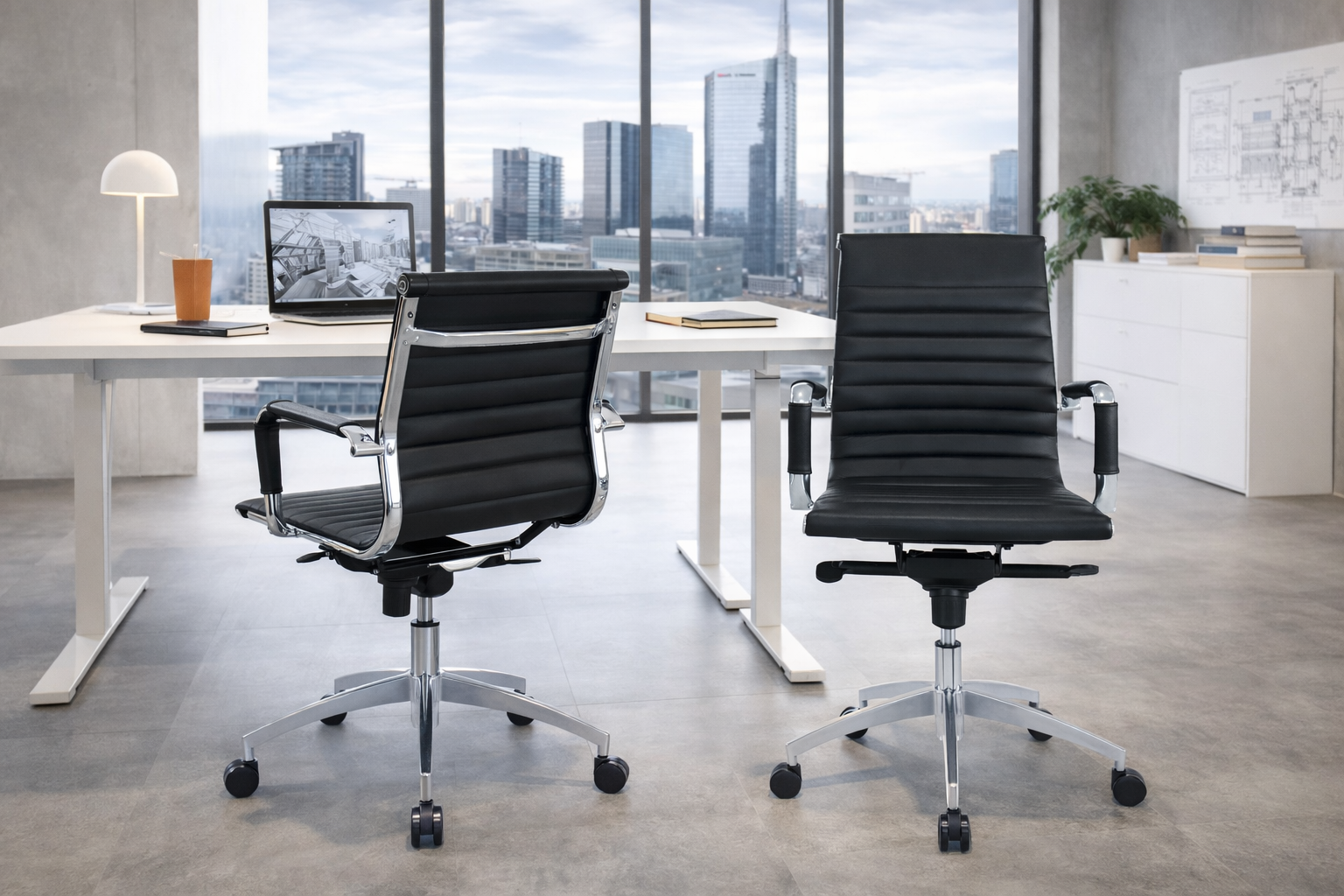 Deux Fauteuils Persée d'Attitudes Bureaux en noir font face à un bureau blanc avec un ordinateur portable, une lampe, une tasse et des livres dans un bureau lumineux avec de grandes fenêtres donnant sur la ville. L'espace présente une décoration minimaliste et un sol gris.