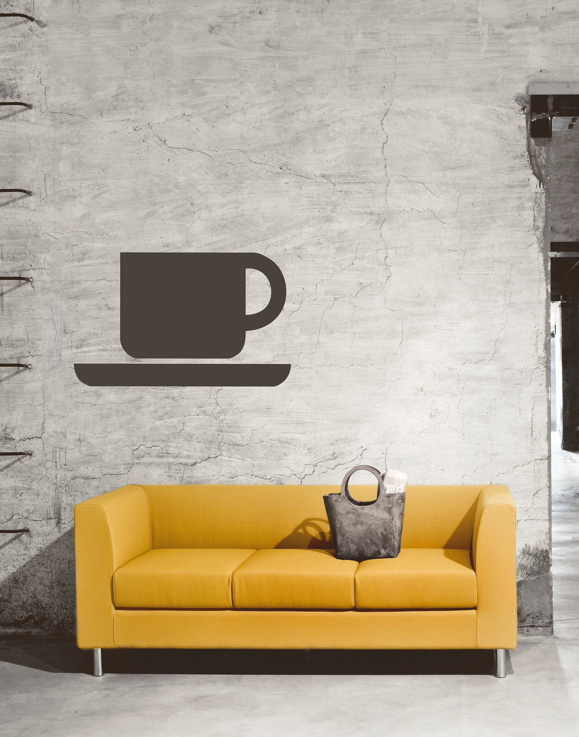 Un canapé modulaire jaune Canapés Domino d'Attitudes Bureaux est posé contre un mur en béton texturé, surmonté d'une tasse et d'une soucoupe noires ; un sac à main gris posé sur l'accoudoir complète le look d'inspiration lounge.