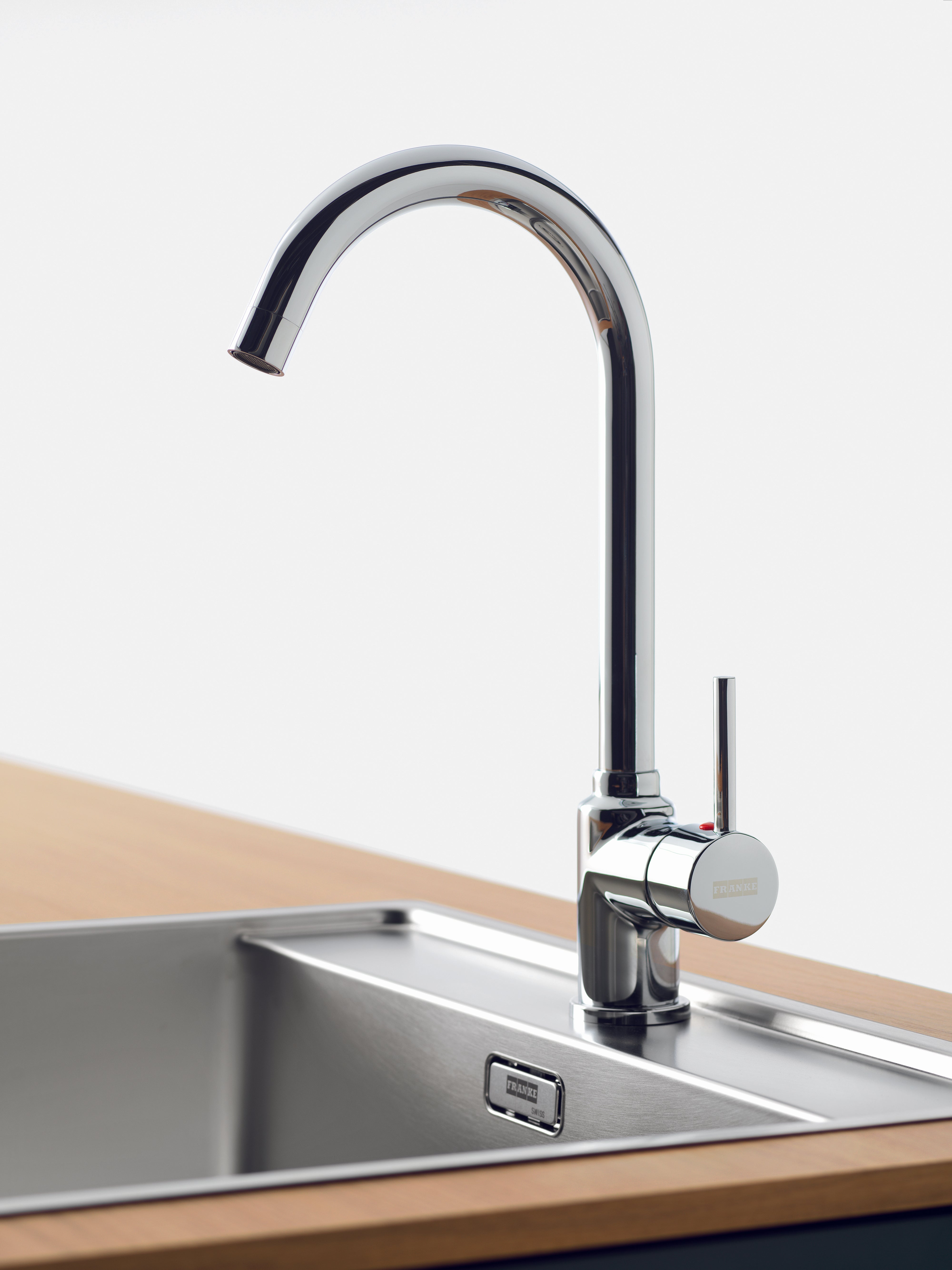 La kitchenette Fluido® d'Attitudes Bureaux est équipée d'un robinet monocommande chromé moderne sur un évier en acier inoxydable, posé sur un plan de travail en bois, idéal pour les salles de pause, le tout présenté sur un fond blanc uni.