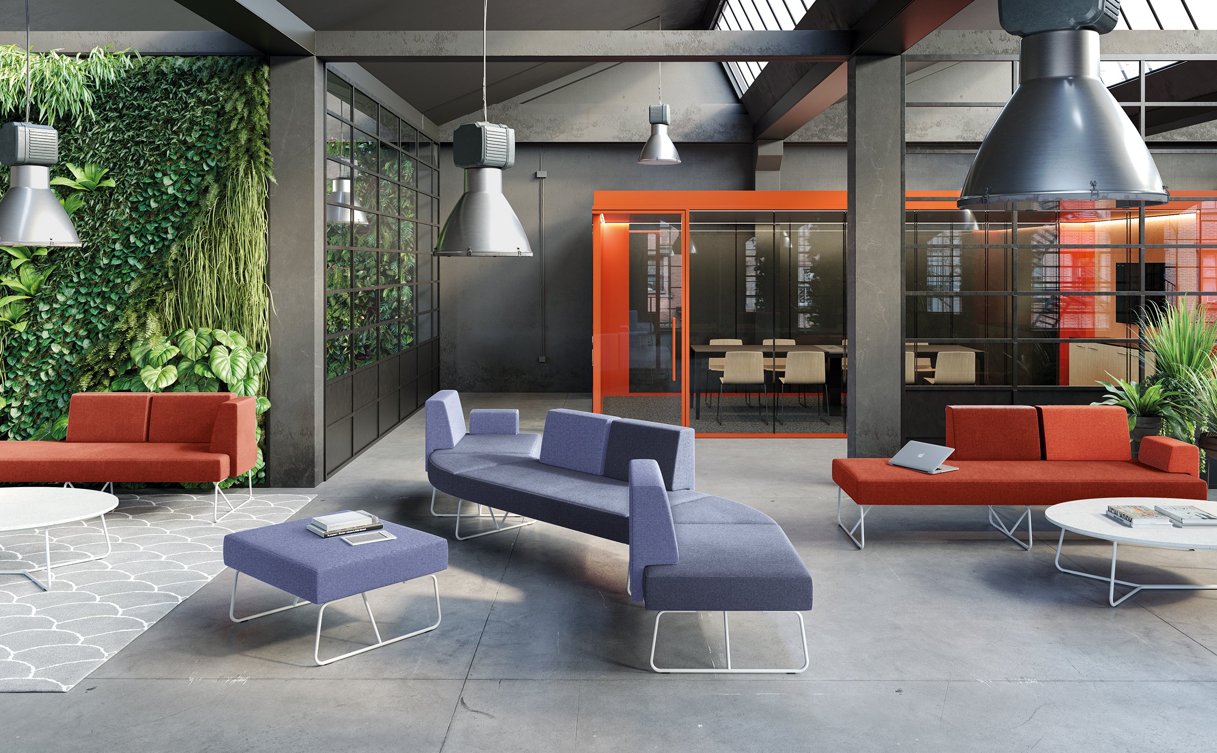 Un salon de bureau moderne présente des Canapés d'accueil Fedra rouges et bleus de d.FLUX, un tapis gris et un mur végétal vert. De grandes lampes industrielles sont suspendues au-dessus, avec en arrière-plan une salle de réunion en verre encadrée d'orange.