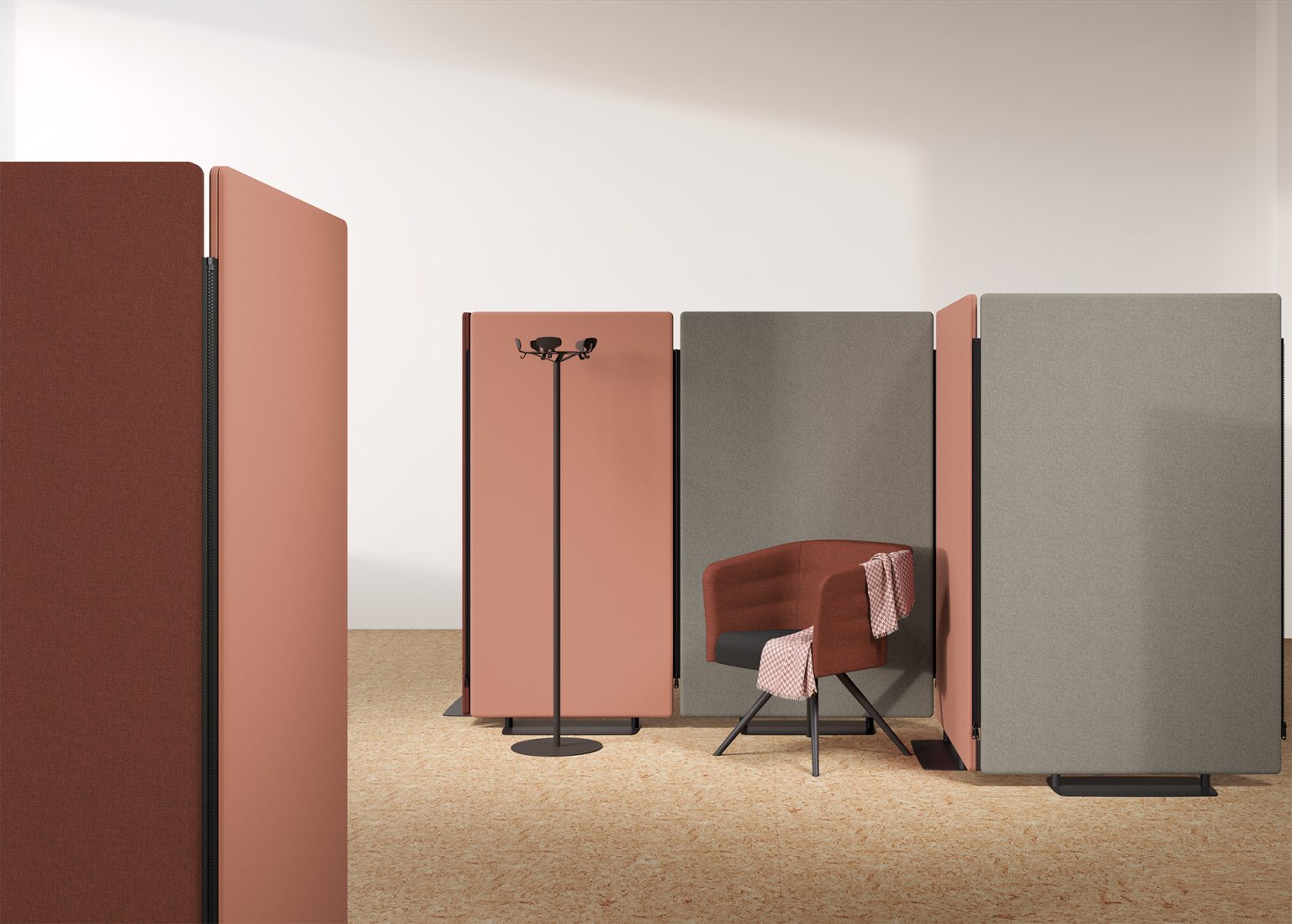 Un bureau moderne avec Attitudes Bureaux Cloisons et écrans acoustiques MADISON en terre cuite et gris, un fauteuil assorti avec un jeté rayé, et un porte-manteau noir sur un sol en liège.