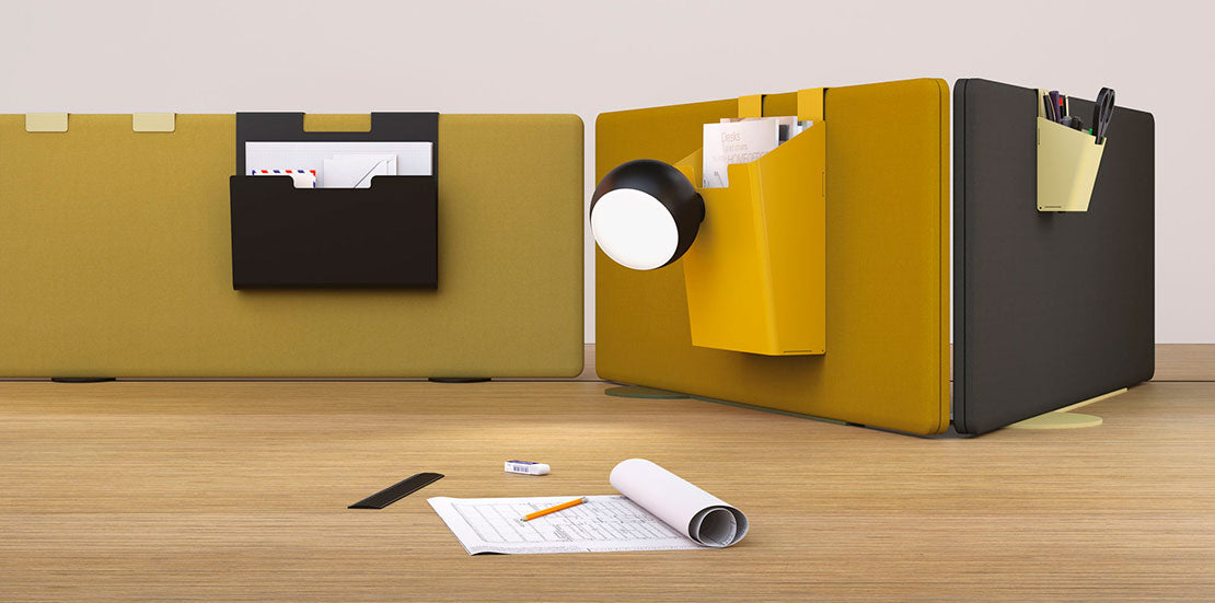 Deux écrans acoustiques MADISON par Attitudes Bureaux : l'un jaune avec un organisateur pour les papiers et une lampe, l'autre noir avec un porte-stylo jaune. En dessous, un bureau contient des papiers, un stylo, une règle et une gomme - parfait pour les espaces de travail modulaires.