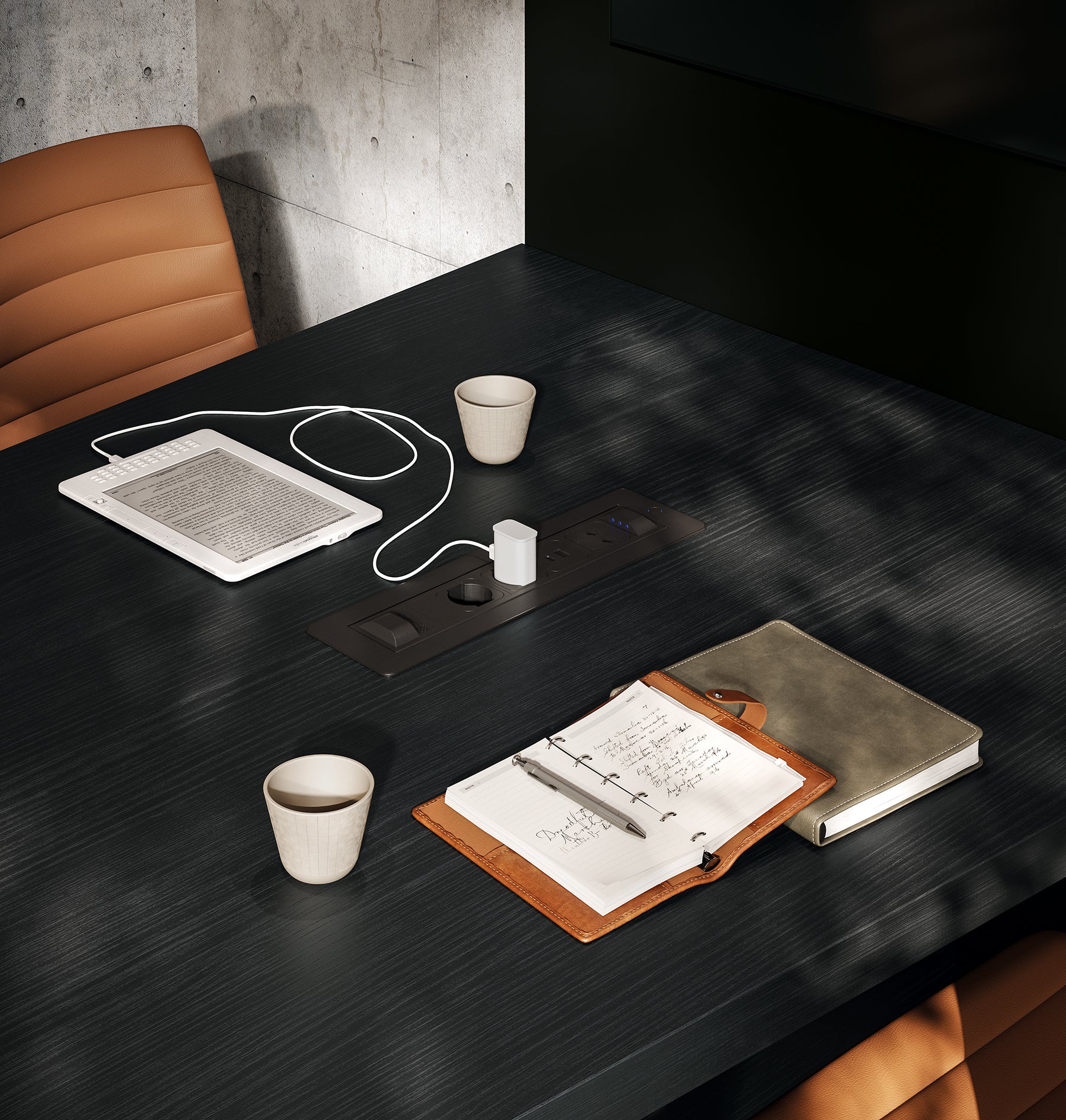 Une table de réunion noire moderne Mux70 de Stefano Boeri Interiors, associée à des chaises marron, accueille deux ordinateurs portables, deux tasses à café, un e-reader avec câble de chargement, un chargeur de tablette et une multiprise intégrée, tandis que la lumière du soleil projette des ombres sur la table.