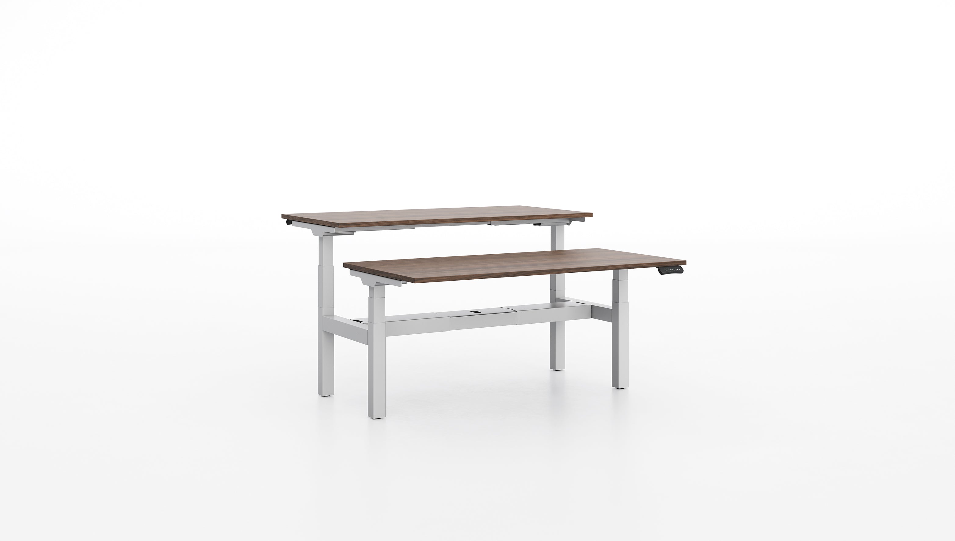 Deux Bureaux réglables en hauteur Pop AD d'Attitudes Bureaux sont présentés, l'un en hauteur et derrière l'autre, sur un fond blanc, mettant en valeur leur polyvalence ergonomique assis-debout avec des pieds en métal gris clair et des plateaux en bois.