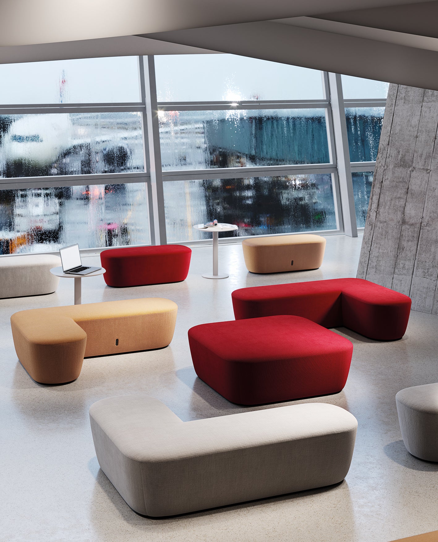 Un salon d'aéroport moderne présente des poufs RADAR colorés de Claesson Koivisto Rune CKR en rouge, beige et gris. Une petite table avec un ordinateur portable et une bouteille d'eau est placée près des fenêtres trempées par la pluie, face à un avion stationné à la porte d'embarquement.