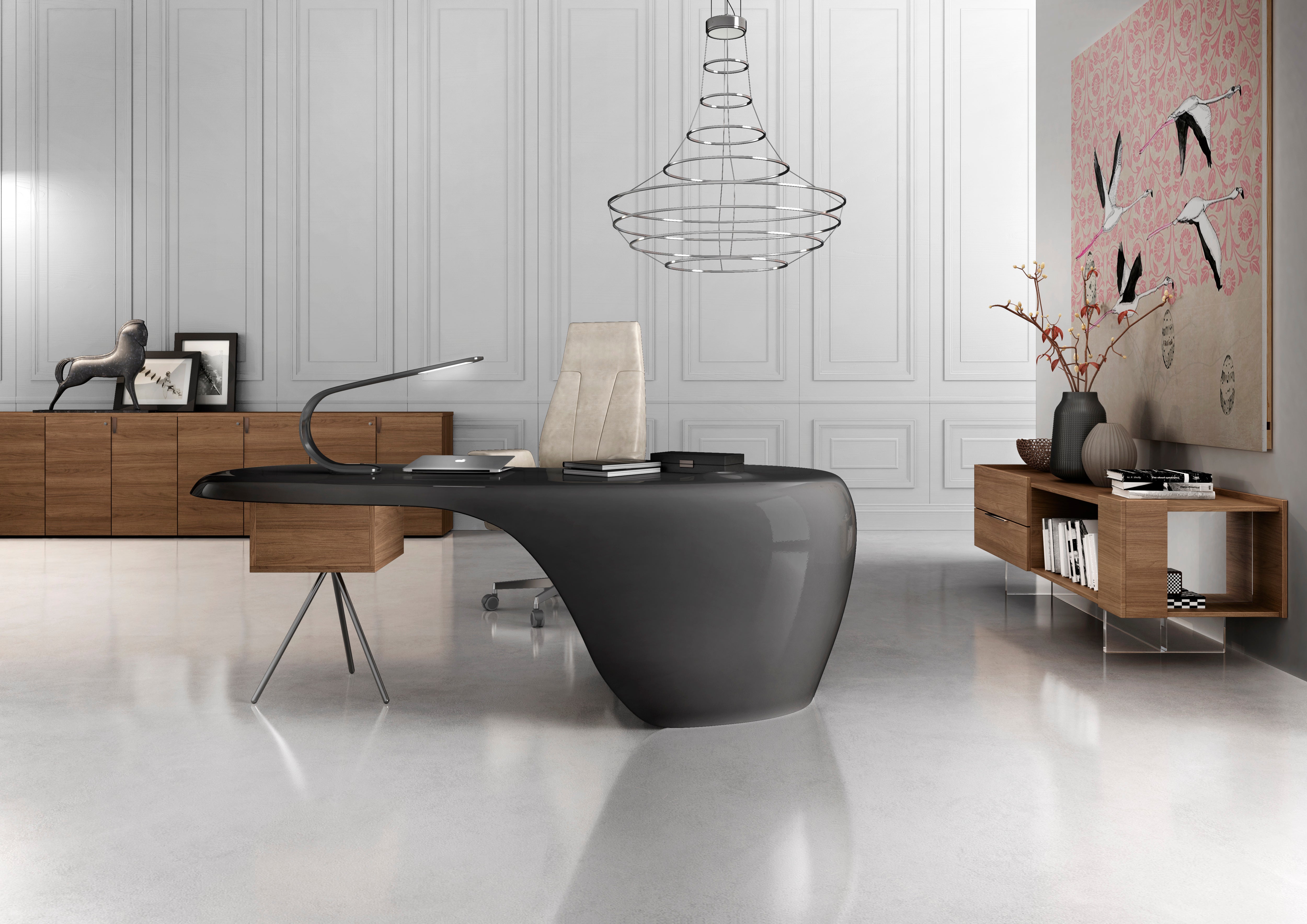 Bureau moderne avec le bureau de direction UNO de Karim Rashid, un fauteuil beige, des armoires en bois, des œuvres d'art abstraites sur le thème des oiseaux, des vases, une lampe et un lustre géométrique, créant ainsi un espace lumineux avec une touche de design caractéristique.