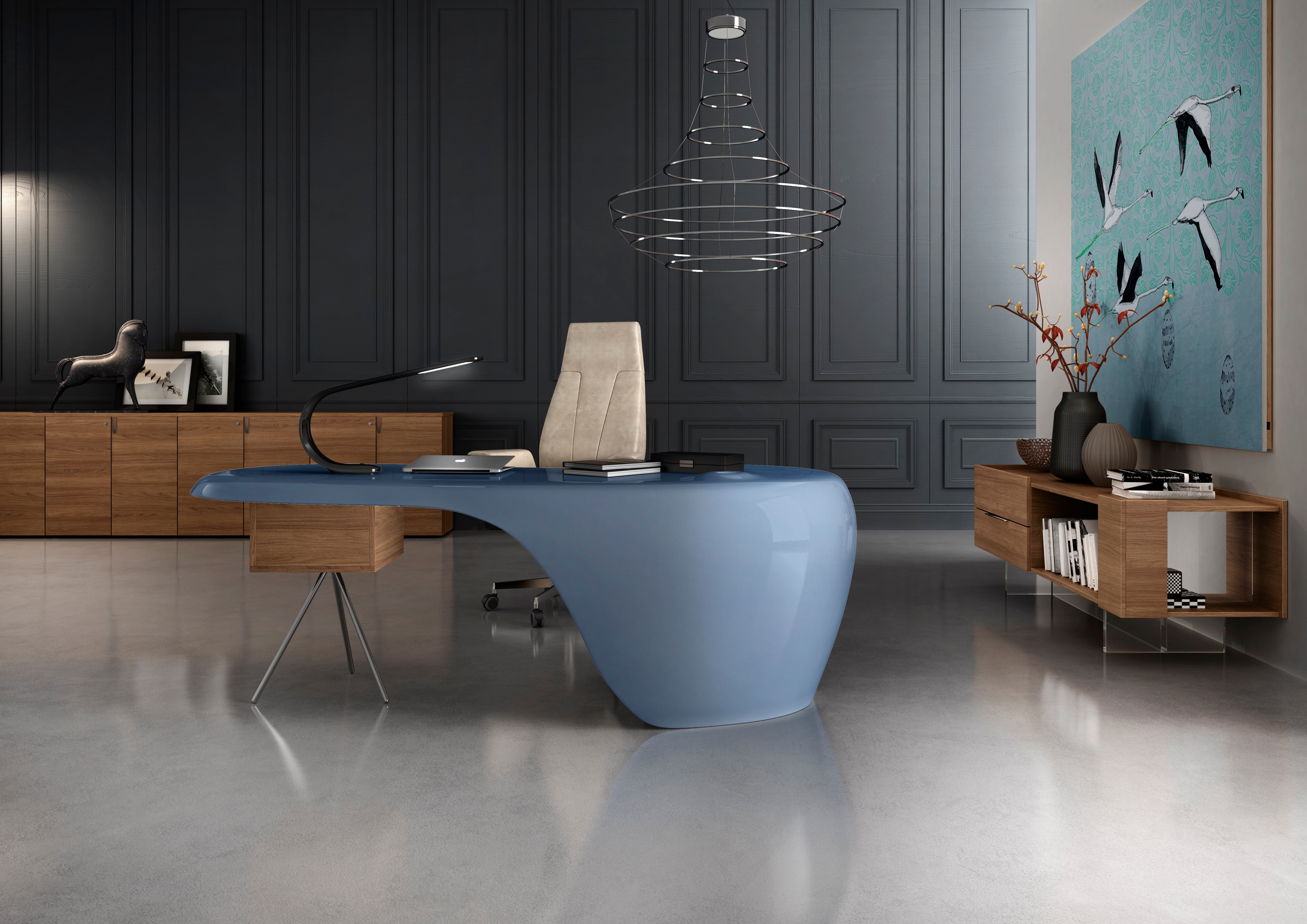 Un bureau moderne présente le bureau de direction UNO de Karim Rashid en bleu sculptural, associé à une chaise beige, des armoires en bois, une lampe abstraite et une œuvre d'art représentant un oiseau ; les tons neutres minimalistes créent une ambiance élégante et contemporaine.
