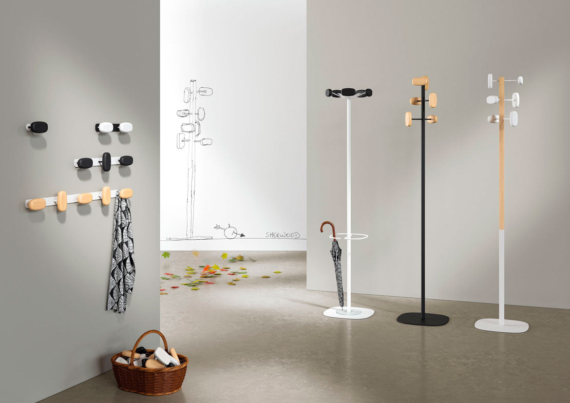 Entrée moderne avec le Portemanteau SHERWOOD d'Emmanuel Gallina, dans un style zen. Des étagères murales et sur pied en noir, blanc et bois avec un parapluie, un panier et des écharpes complètent le look chaleureux bois et acier.