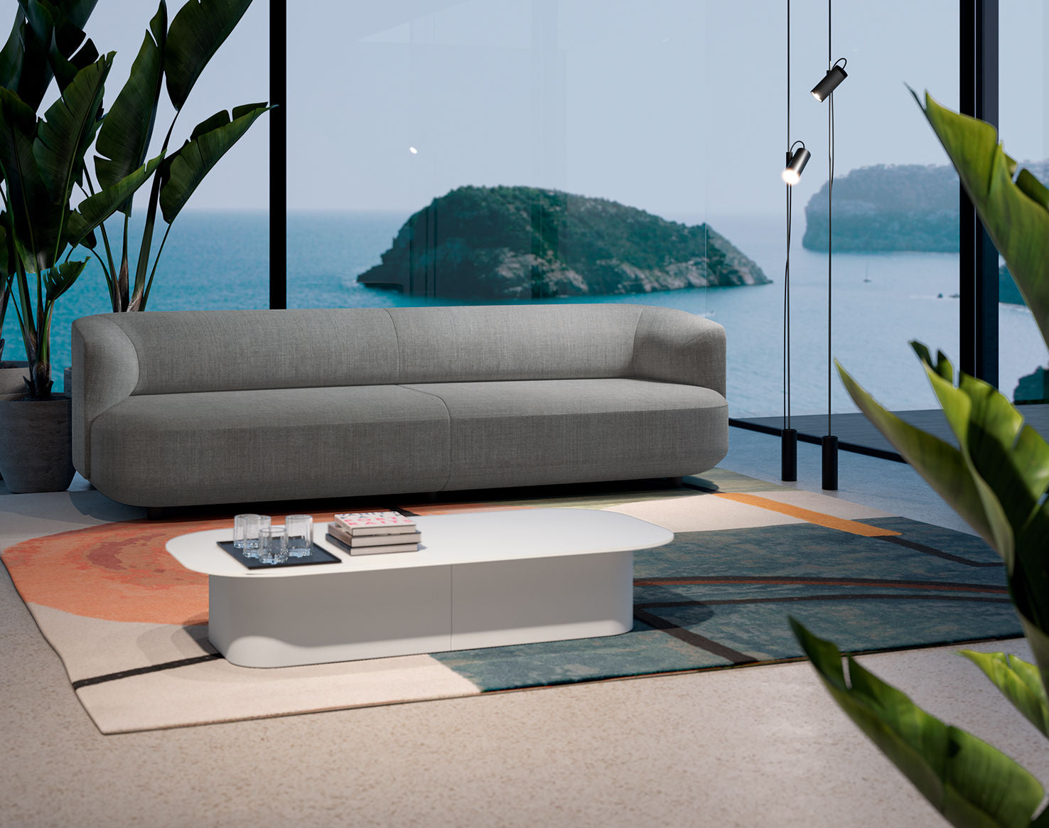 Un salon moderne avec un canapé gris, des tables basses Ramos Bassols Afina avec des livres et des verres, un tapis géométrique coloré, de grandes plantes en pot et des fenêtres du sol au plafond donnant sur l'océan et les îles lointaines.