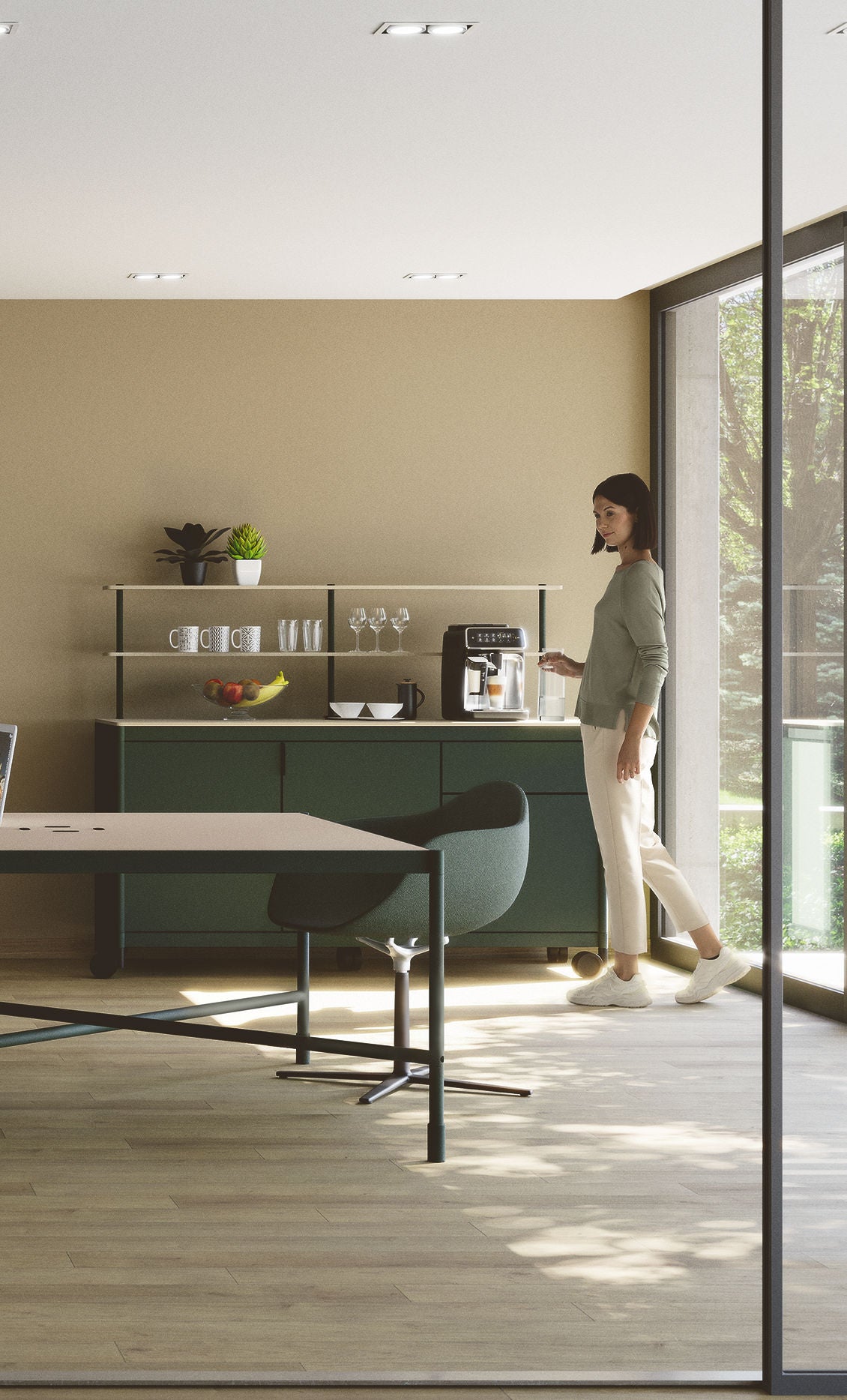 Une femme prépare une boisson à la machine à café dans la Kitchenette Fluido® d'Attitudes Bureaux, avec des tons neutres, des étagères avec des tasses et des plantes, et de grandes fenêtres qui remplissent l'espace pause de lumière naturelle.