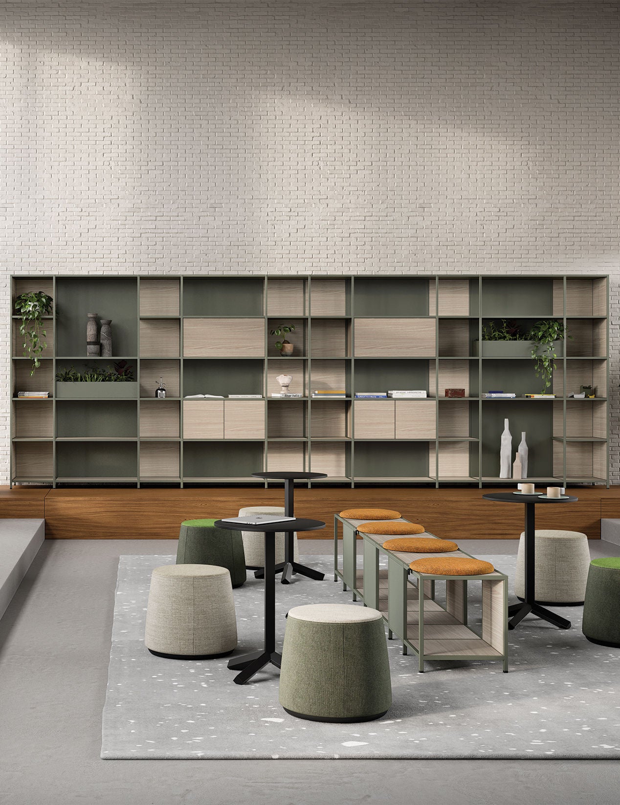 Salon moderne comprenant la Bibliothèque de bureau modulaire Phylo d'Attitudes Bureaux, des tables minimalistes, des tabourets verts et havane, un tapis à motifs gris sur un sol clair, des étagères avec des plantes et des livres, et un mur de briques blanches en toile de fond.